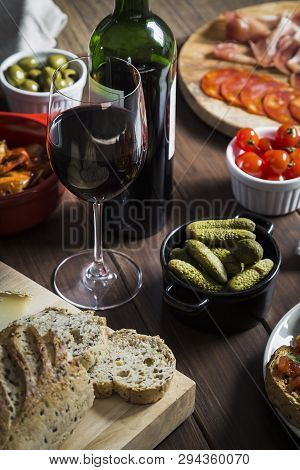 Wine And Tapas Dishes On A Wooden Table. Dishes Include Garlic Prawns, Bread And Cheese, Meat And Ch