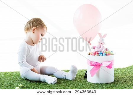 Cute Baby Sitting Near Box With Estern Eggs, Decorative Rabbit And Air Balloon Isolated On White