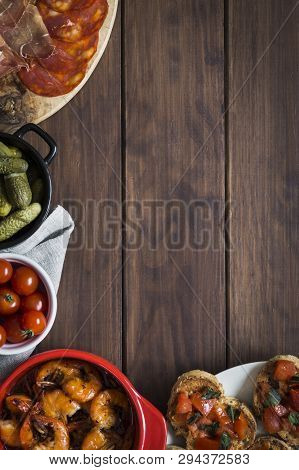 Tapas Dishes Around Edges With Clear Copy Space. Dishes Include Tomato Toasts, Garlic Prawns, Cherry