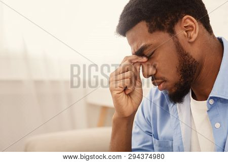 Depressed African American Guy Touching His Nosebridge And Keeping Eyes Closed, Empty Space