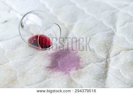 Wine Glass Spilled On Bed. Dropped Wineglass On White Bed Sheet. Pink Wet Stain. Unlucky, Unfortunat