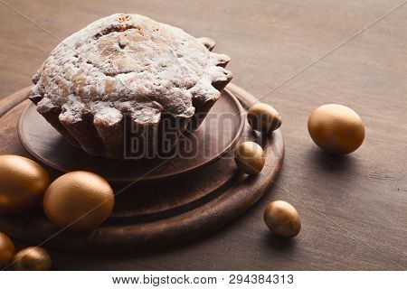Easter Cake Sprinkled With Powder And Golden Eggs On Wooden Table