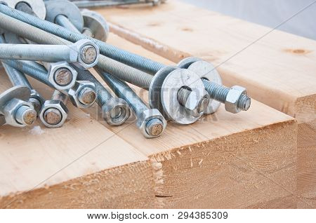 Bolts And Nuts On On The Background Of Wooden Boards. Hardware For Fastening Wooden Beams. Bolted Co