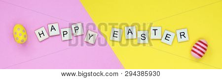 Happy Easter Spelled Out On Wooden Tiles, On A Pink And Yellow Banner