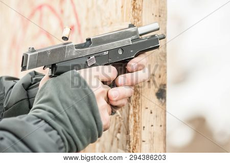 Close-up Detail View Of Shooter Hands Holding Gun And Shooting