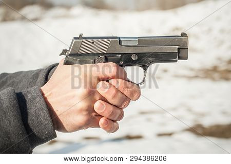 Close-up Detail View Of Shooter Hands Holding Gun And Shooting