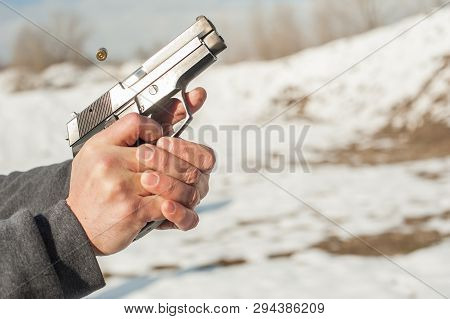 Close-up Detail View Of Shooter Hands Holding Gun And Shooting