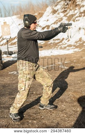 Shooter Holding Gun In Hand And Shooting. Close-up Detail View
