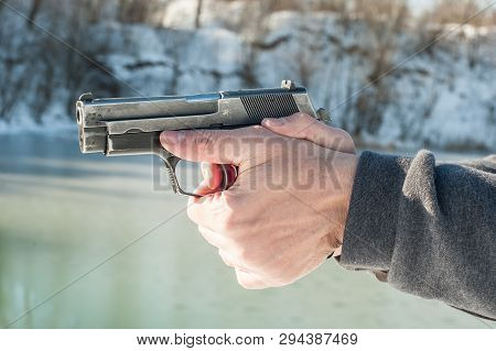 Shooter Holding Gun And Shooting On Winter Lake Water Background
