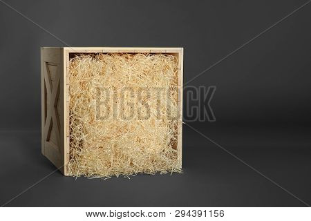 Wooden Crate With Shavings On Dark Background, Space For Text