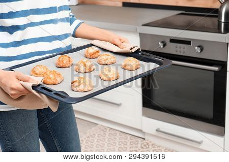 Young Woman With Sheet Pan Of Oven Baked Cookies In Kitchen, Closeup
