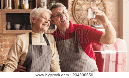 Capturing Lovely Moments. Cheerful Senior Couple Taking Selfie On Smartphone In Kitchen, Panorama