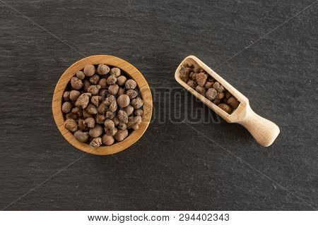 Lot Of Whole Brown Clay Pebbles (leca) With Wooden Bowl And Wooden Scoop Flatlay On Grey Stone