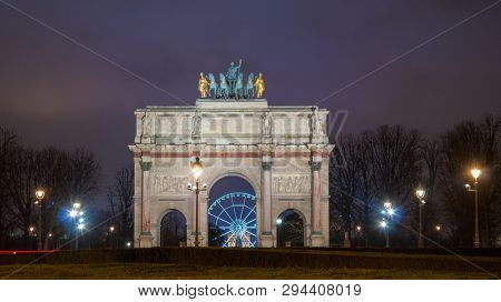 Paris, France - August 04, 2006: Night panorama of the Triumphal arch du Carrousel on the background of the Ferris wheel and luminous street lamps