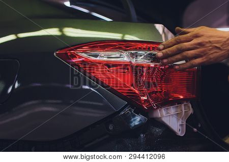 Mechanic Matching Automobile Headlight Lamp To Damaged Car At Repair Service Station.