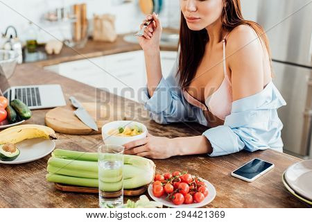 Cropped View Of Sexy Girl In Bra And Shirt Eating Fruit Salad In Kitchen