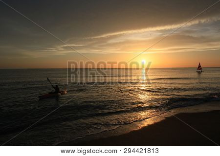 Captiva Island, Florida 08-05-2015 Kayaker And Small Sailboat In Partial Silhouette Against The Sett