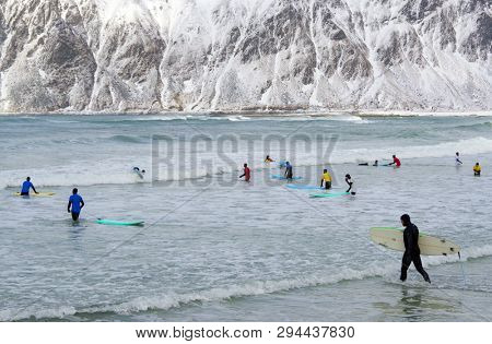 FLAKSTAD BEACH, LOFOTEN ARCHIPELAGO, 26 MARCH, 2019: Young men surfing in arctic conditions at Flakstag Beach, Lofoten, Norway, Europe