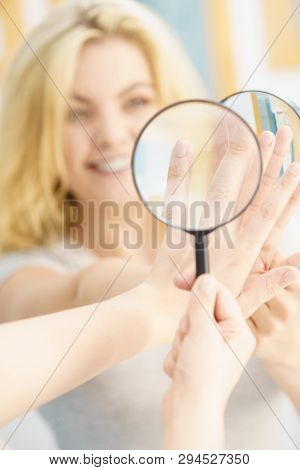 Beautiful Perfectionist Young Woman Checking Her Finger Nails Through Manifying Loupe Glass.