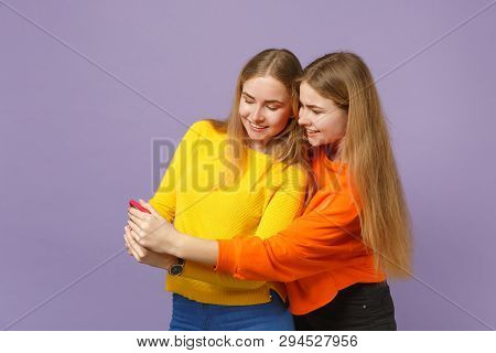 Two Smiling Young Blonde Twins Sisters Girls In Vivid Clothes Using Mobile Phone Typing Sms Message 