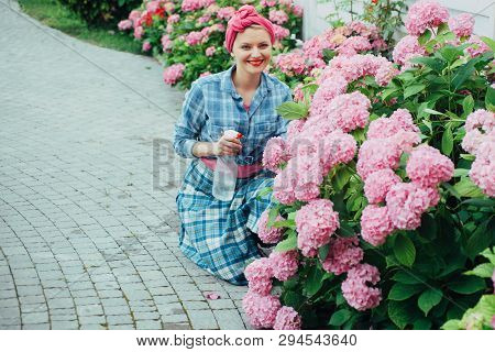 Woman Care Of Flowers In Garden. Flower Care And Watering. Soils And Fertilizers. Greenhouse Flowers