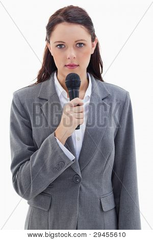 Close-up of a serious businesswoman holding a microphone against white background
