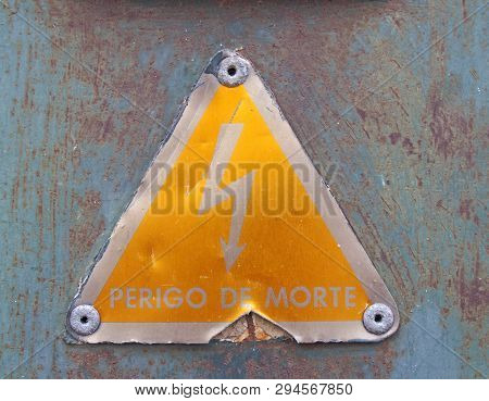 An Old Metal Triangular Yellow Portuguese Electricity Safety Sign With A Lightning Bold Symbol Readi