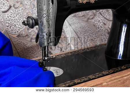 Sewing Head Of Antique Sewing Machine With Presser Foot During Hemming Bright Blue Fabric Close Up
