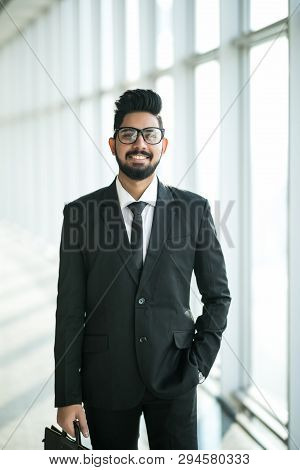 Indian Businessman Walking In Office Interior With Big Windows With View On The Business Center