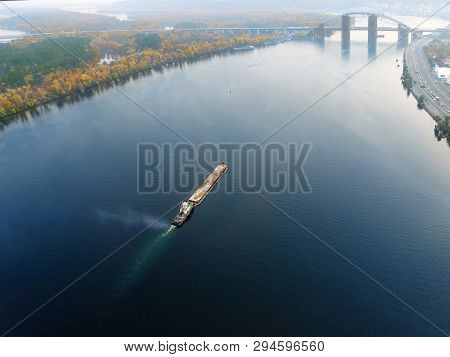 Scenic Aerial Cityscape Of Kiev And River Dnipro At Sunset. Tugboat Supporting Barge With Sand Bulk 