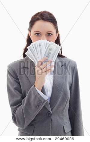 Close-up of a businesswoman hiding behind a lot of dollar bank notes against white background