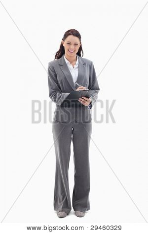 Businesswoman smiling while writing on a clipboard against white background