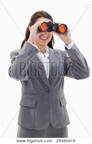 Close-up of a businesswoman smiling and looking through binoculars on the left side against white background