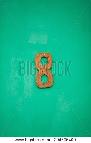 Wooden Figure Eight Number On Emerald Wall. Design Exterior In Emerald Green Virid Tones