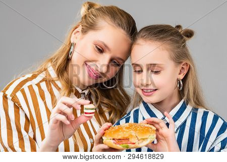 Appealing Good-looking Positive Girls Comparing Different Sizes Of Burgers