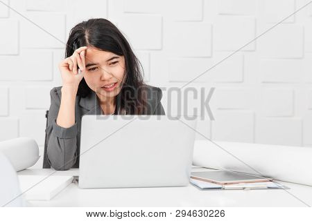 Shot Of Young Beautiful Asian Architect In Business Casual, Pen In Hand Looking At Laptop Screen, Re