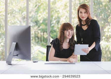Portrait Of Two Beautiful Asian Successful Businesswomen In Black Dresses Busily Working In Modern O