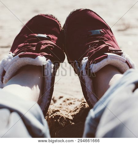 Feet Of Young Woman In Sport Footwear And Jeans Relaxing After Hiking On Sand Beach. Square Pov. Adv