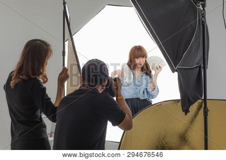 Photographer And Stylist Team Working On Studio Portrait Of Young Beautiful Asian Woman With Dark Br