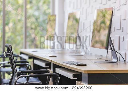 Computer Screen In Modern Office With Reflection Of Green Leaves And Tree Outside Window In Backgrou
