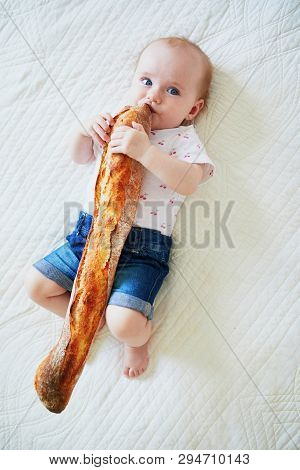 Six Months Old Baby Girl Eating Traditional French Bread (baguette). Introducing Solids To Infant Ki