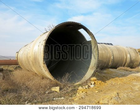 Old Rye Pipes Of Large Diameter Lie On The Ground. Pipeline. Large Iron Drainage Pipes Connect Two R