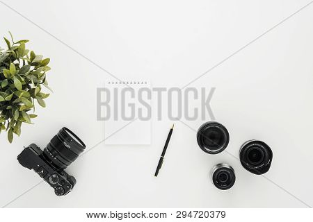 Mocap Work Photographer On A White Table. Flat Lay Mirrorless Camera, A Few Lenses And A Notebook Wi