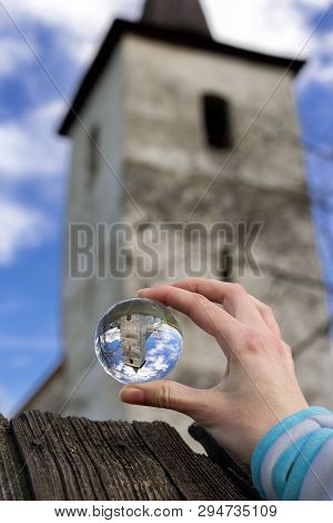 Crystal Lensball In Hand And Ancient Gothic Church Of All Saints Ludrova, Slovakia