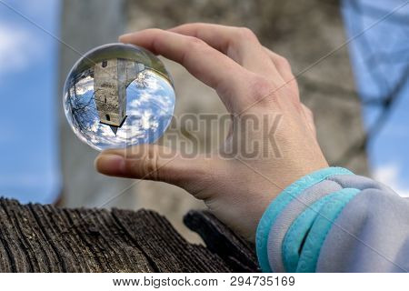 Crystal Lensball In Hand And Ancient Gothic Church Of All Saints Ludrova, Slovakia