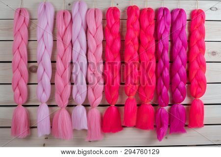 Kanekalon Hangs On A Wooden Background Of Pink, Fuchsia Red In Different Shades Similar