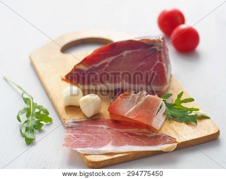 Thin Piece Of Flesh Upon White Table. Prosciutto, Prsut, Or Spanish Jamon With Cherry Tomatoes, Fres