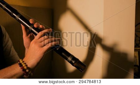 Man Playing Japanese Bamboo Flute - Shakuhachi. Warm Romantic Illumination, Low Key. Relaxation, Med