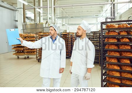 The Technologist And Baker Speak In A Bread Factory.