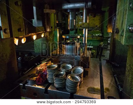 Dirty Used Low Tech Stamping Press Producing Round Aliminium Parts In Dark Environment